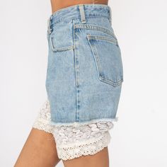 "Vintage 80s cut off denim shorts in blue denim with lace trim. Every garment we sell is authentic vintage and one-of-a-kind! You will receive the exact item photographed. Condition: Very good vintage. Has a couple faint spots that should come out with cleaning. Best fits women's: Extra small/24 Material: denim MEASUREMENTS Taken from seam to seam while the garment is lying flat. Double the armpit, waist, and hips For reference, model is 5'10\" and measures 31-23-34. Waist: 12\" Hips: 19\" Insea Denim Bottoms With Lace Trim For Summer, Summer Denim Bottoms With Lace Trim, Spring Shorts With Lace Trim, Lace Trim Shorts For Spring, Fitted Denim Bottoms With Lace Trim, Vintage Bottoms With Lace Trim For Summer, Vintage Lace Trim Bottoms For Summer, Short Leg Bottoms With Lace Trim For Spring, Spring High-waisted Shorts With Lace Trim