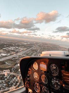 the view from inside an airplane looking down on a city and sky with clouds in the background