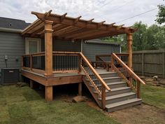 a wooden deck with steps leading up to it and a pergolan roof over the top