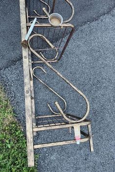 a metal rack with cups on it sitting in the middle of some grass next to a street