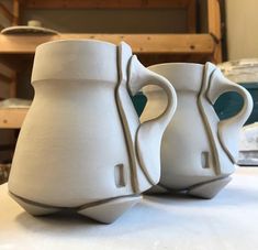 two white vases sitting on top of a table