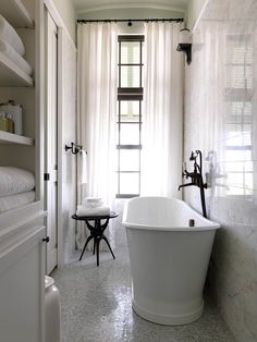 a white bath tub sitting in a bathroom next to a window