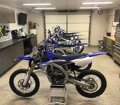 several dirt bikes are lined up in a garage