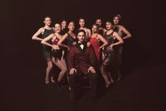 a man in a tuxedo poses with dancers