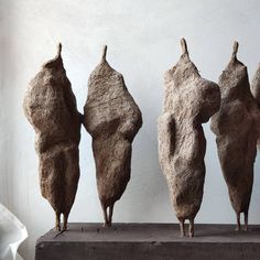 three sculptures made out of clay sitting on top of a wooden table next to a white wall