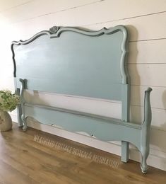 a blue headboard sitting on top of a wooden floor next to a potted plant