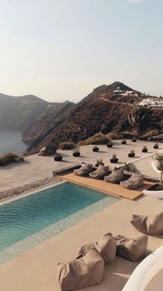 an outdoor swimming pool with lounge chairs and mountains in the background