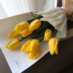 a bouquet of yellow tulips sitting on top of a piece of paper