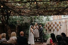 the bride and groom are getting married in an outdoor ceremony with greenery on the wall