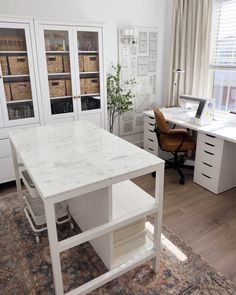 a white desk sitting in the middle of a living room next to a book shelf