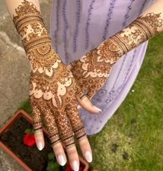 a woman's hands with hennap on her hand and flowers in the background