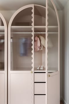 an arched closet with clothes and shoes on the shelves next to it is shown in this image