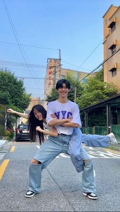 two people standing in the middle of an empty street, one holding another person on his back