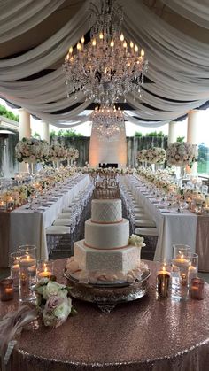 a wedding cake sitting on top of a table under a chandelier