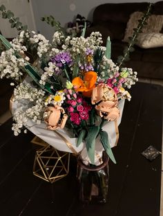 a vase filled with lots of colorful flowers on top of a wooden table next to a couch