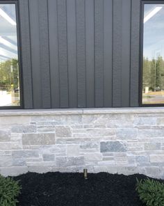 there is a window on the side of a building that has plants in front of it