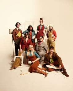 a group of people posing in front of a white wall with an easel on the floor