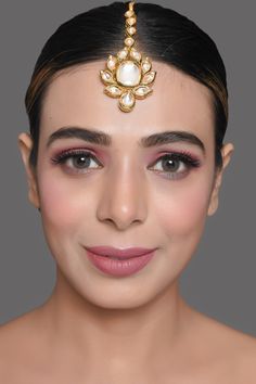 a woman wearing a gold head piece with pearls on the top and bottom of her head