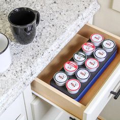 an open drawer in a kitchen with coffee cups