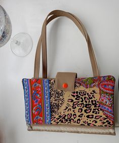 an animal print purse is hanging on the wall next to a wine glass and bottle