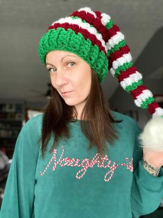 a woman wearing a christmas hat holding a white ball in her right hand and looking at the camera