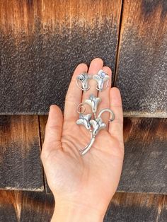 This Art Nouveau style set includes a brooch and screw back earrings with flower shapes reminiscent of calla lilies. The pieces have a matte-like finish and pleated details with flowing and curving stems. One of the earring backs is more bent than the other and the set is being sold in as is condition for this reason. The scew backs are also marked, 'Sterling'. The brooch is 3 inches long and each earring is just over 1 inch long. Silver Brass Flower-shaped Earrings, Adjustable Nickel-free Sterling Silver Flower Earrings, Adjustable Sterling Silver Flower-shaped Earrings, Silver Art Nouveau Brooches As Gift, Silver Art Nouveau Brooches For Gifts, Screw Back Earrings, Calla Lily, Earring Backs, Flower Shape