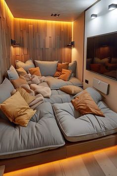 a large couch with many pillows on top of it in front of a wall mounted television