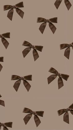 brown bows are flying in the air on a beige background with no one is wearing them