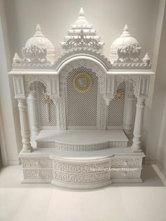 an ornate white bench in the corner of a room with columns and arches around it