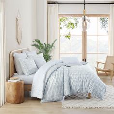 a bed in a bedroom with white walls and wooden flooring next to a window