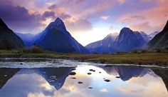 the mountains are reflected in the still water at sunset with clouds and reflections on the surface