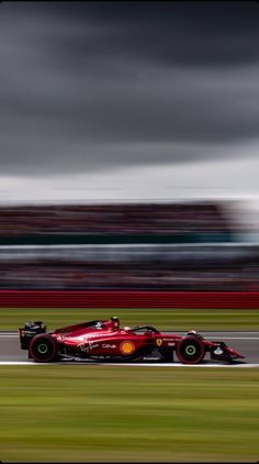 a red race car driving on a track with motion blurry in the foreground