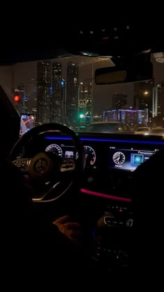 the interior of a car at night with city lights in the background and illuminated dashboard