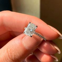 a woman's hand holding an engagement ring with a diamond in the middle and side