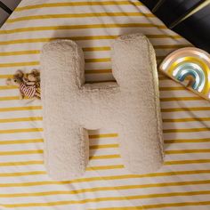 the letter h is made out of white and yellow striped material with a teddy bear next to it