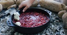 someone is cooking food in a pot on the ground with some potatoes and other items