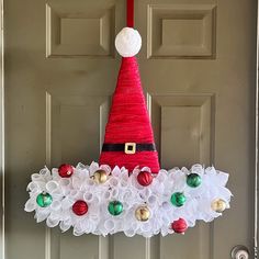 a christmas wreath hanging on the front door with santa's hat and ornaments around it