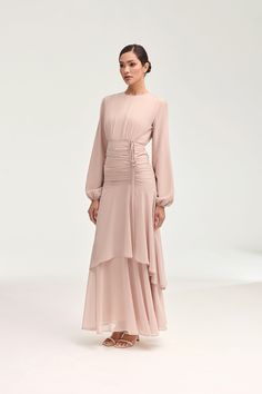 Introducing the Narjis Side Rouched Maxi Dress in Jasmine Pink. Embrace the exquisite side rouched detailing and asymmetrical tier design that flatters every figure. With elegant balloon sleeves and a flowy chiffon fabric, this dress is a timeless piece for any occasion. Elevate your wardrobe with this luxurious dress. Model is 5'7" and is wearing size XS/58". Elegant Long Sleeve Dresses With Ruched Sides, Feminine Lantern Sleeve Ruched Dresses, Billowy Ruched Midi Dress For Evening, Feminine Long Sleeve Ruched Maxi Dress, Billowy Ruched Maxi Dress With Puff Sleeves, Billowy Ruched Midi Dress For Party, Modest Ruched Dress With Puff Sleeves, Flowy Ruched Maxi Dress With Puff Sleeves, Billowy Ruched Maxi Dress For Parties