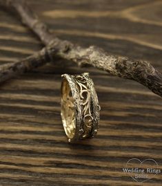 the wedding ring is sitting on top of a piece of drift wood with a branch in the background