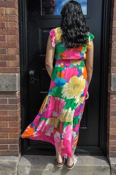 The Flowy Multi-Color Floral Chiffon Tiered Maxi Dress is a stunning display of elegance and vibrant design, perfect for any festive occasion or casual outing. This dress is crafted from 100% polyester chiffon, a fabric known for its light, airy qualities and excellent durability. The chiffon ensures a breezy feel with a graceful drape that complements the tiered structure of the maxi dress. Adorned with a lively floral print in a myriad of colors, the dress captures the essence of spring and su Multicolor Floral Printed Dress For Garden Party, Multicolor Floral Dress With Vibrant Print For Garden Party, Vibrant Multicolor Floral Dress For Garden Party, Vibrant Multicolor Maxi Dress With Tropical Print, Colorful Floral Print Dress For Garden Party, Multicolor Printed Midi Dress For Garden Party, Multicolor Chiffon Maxi Dress, Summer Multicolor Chiffon Dress For Garden Party, Green Chiffon Midi Dress With Floral Print