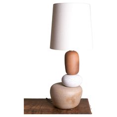 a lamp that is sitting on top of a rock with a wooden base and a white shade