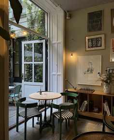 a table and chairs in a room with pictures hanging on the wall above it's windows