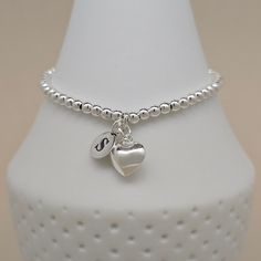 This gorgeous personalised silver-plated bead bracelet has a stunning polished silver heart charm. Personalise the bracelet with solid silver letter charms. The bracelet is available in a standard 16cm size or larger 19cm size. Threaded onto strong jewellery elastic. If you would like two or three letter charms adding to your bracelet, please select the relevant option from the 'Letter Charm' option box. Please then let us know, in the personalisation box, which letters you would like. Our free Sterling Silver Name Bracelet With Heart Charm For Gift, Silver Heart-shaped Name Bracelet For Personalized Gift, Silver Heart Name Bracelet For Personalized Gift, Personalized Silver Name Bracelet With Heart Shape, Dainty Personalized Silver Heart Bracelet, Silver Heart Bracelet With Name, Silver Name Bracelet With Heart Charm For Gift, Silver Name Bracelet With Heart Charm As Gift, Silver Name Bracelet With Heart Charm