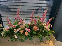 pink flowers and greenery in a vase on a window sill