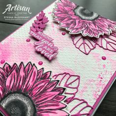 a pink and white card with sunflowers in the middle, on top of a table