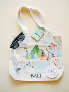 a bag with various items on it sitting on a table next to a pair of sunglasses