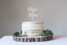 a white cake with greenery on top sitting on a table