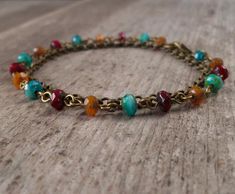 a gold chain bracelet with multi colored beads