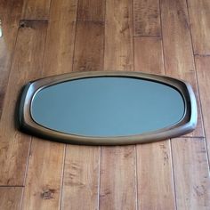 a mirror sitting on top of a wooden floor next to a wall mounted toilet paper dispenser