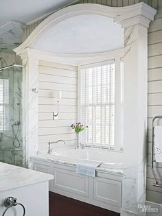 a bathroom with a tub, sink and shower in it's corner area next to a window